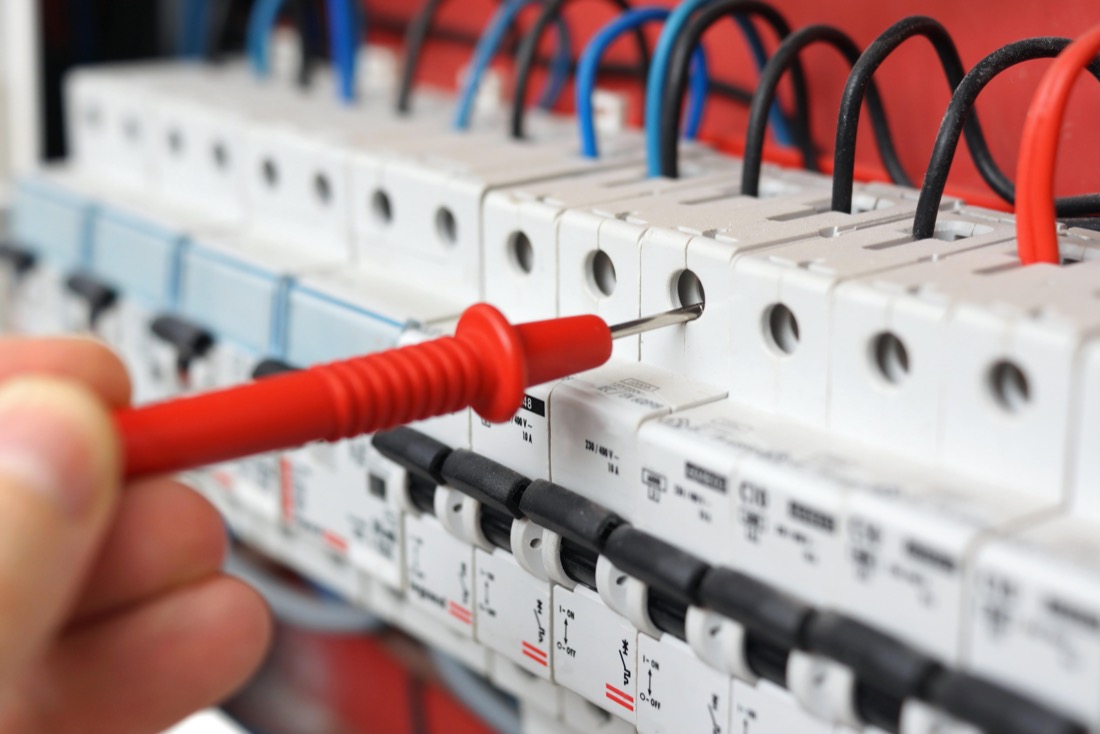 Electrician's hand with multimeter testing electronics Electricians in Edinburgh