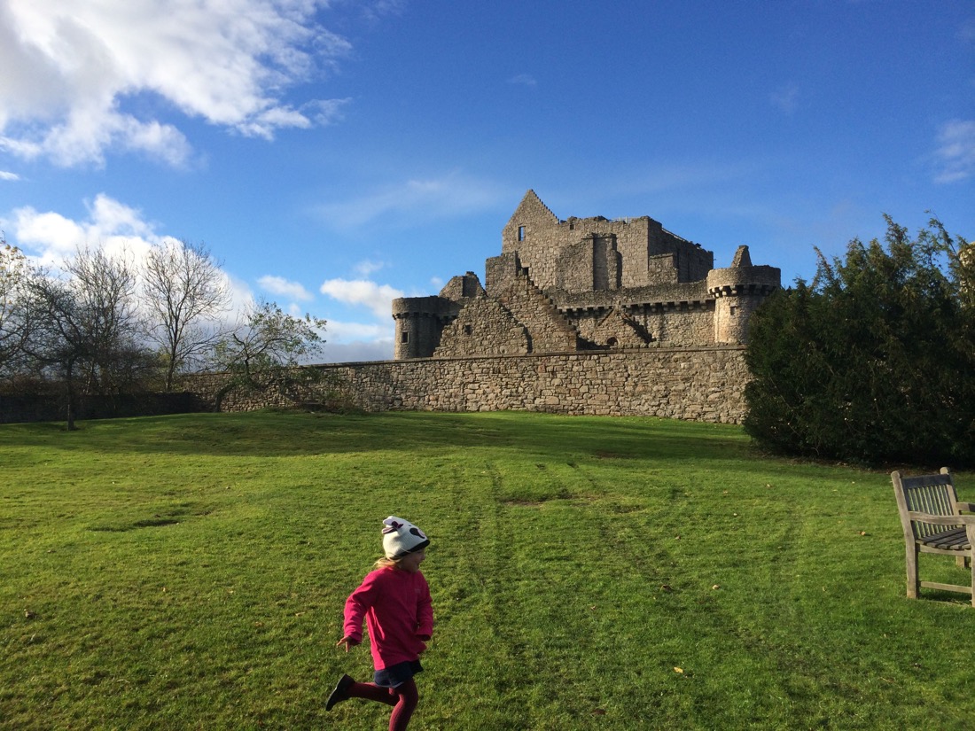 young girl running blue skies over Craigmillar Castle in Edinburgh