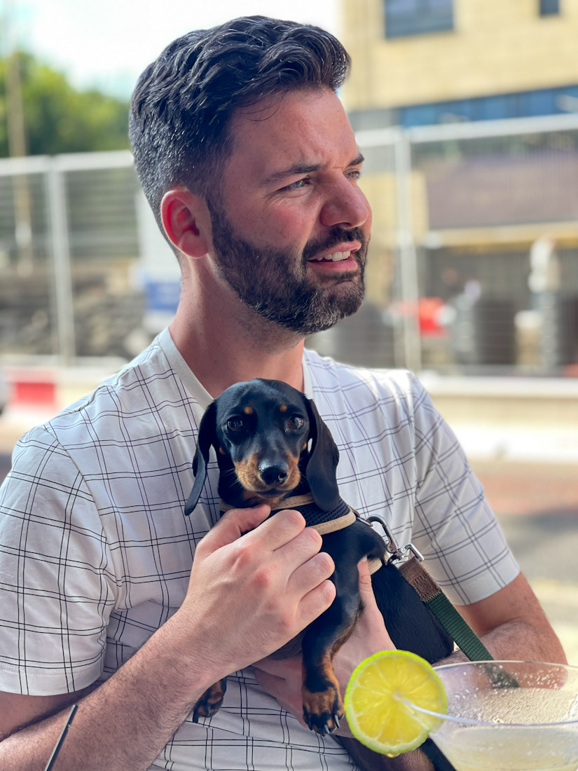 Man with beard holding small dog at pub
