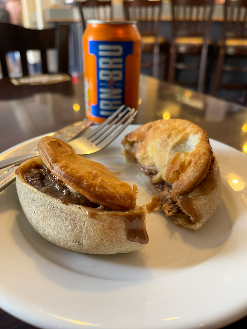 Small steak pie on plate with tin of Irn Bru in background