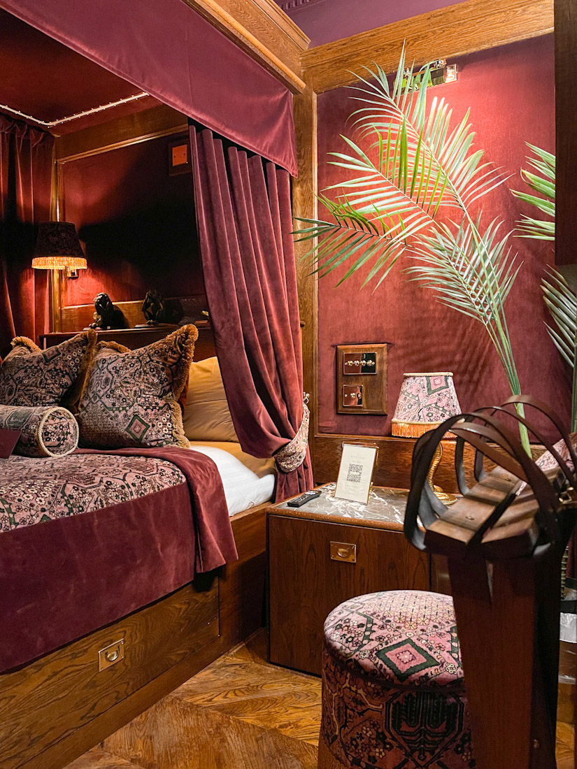 Four post bed with dark red drapes at House of Gods 