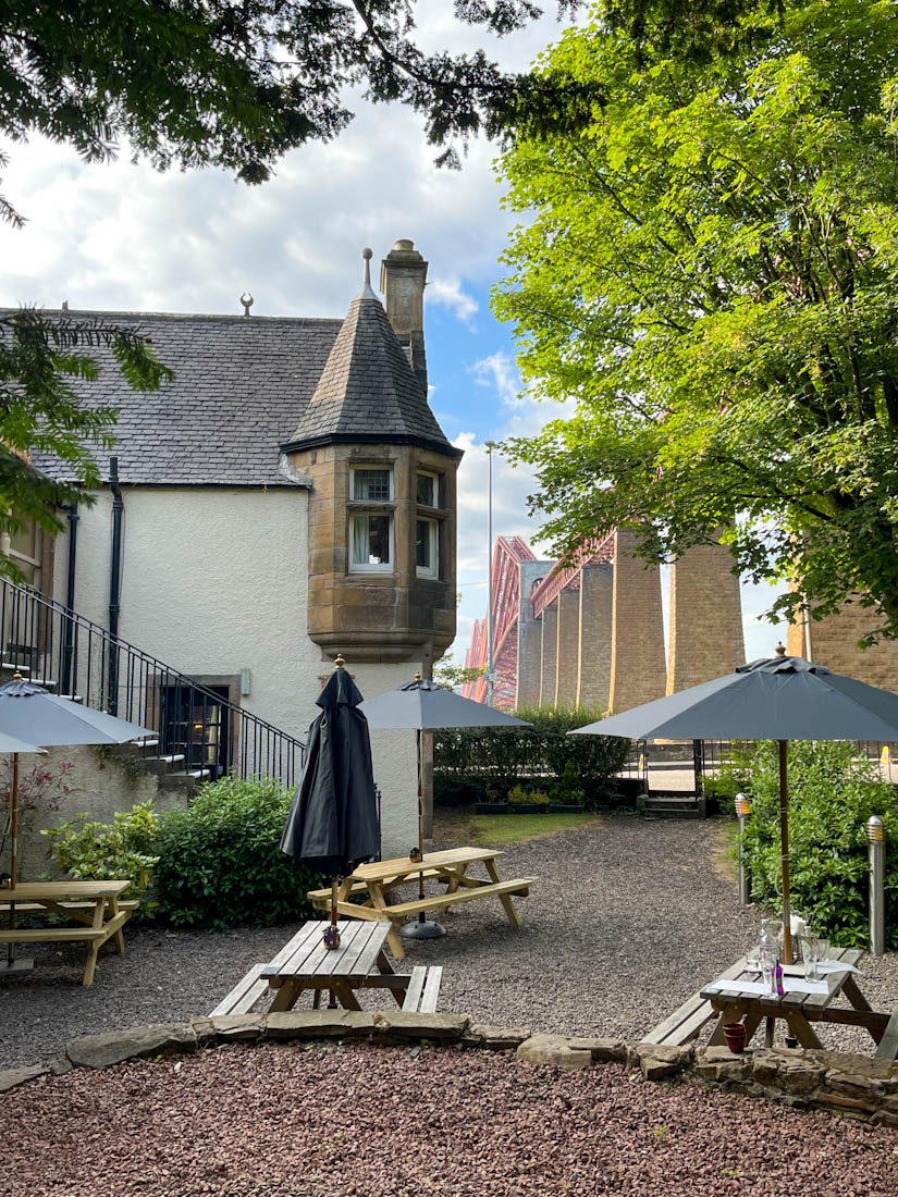 Hawes Inn South Queensferry hotel beer garden with green trees and Forth Bridge in view