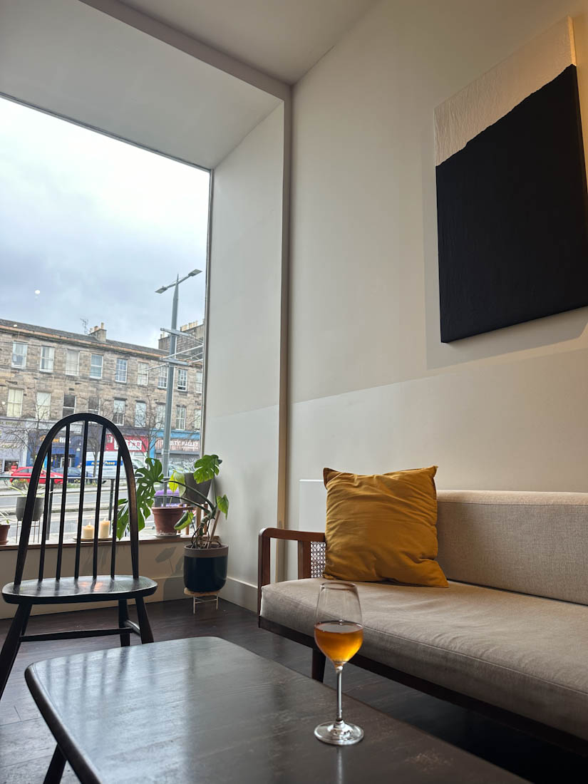 Gentle neutral decor of Spry Wine Bar Edinburgh with glass of orange wine on table